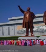 North Korean women bowing in traditional clothing to statues Kim il-Sung and Kim Jong-il Pyongyang