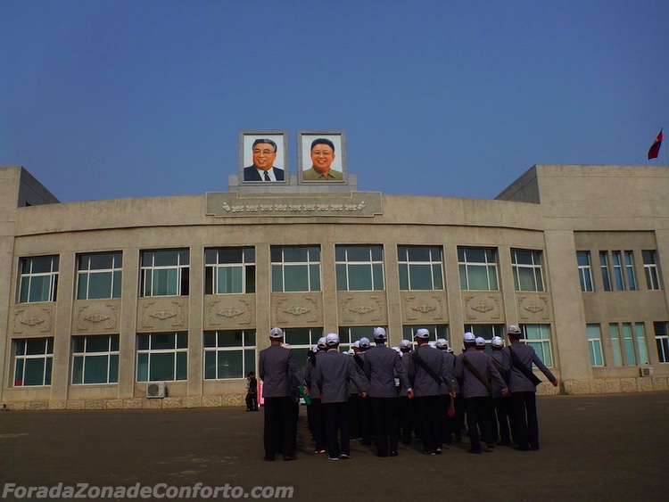 Trabalhadores marchando sob os retratos de Kim Sung-il e Kim Jong-il