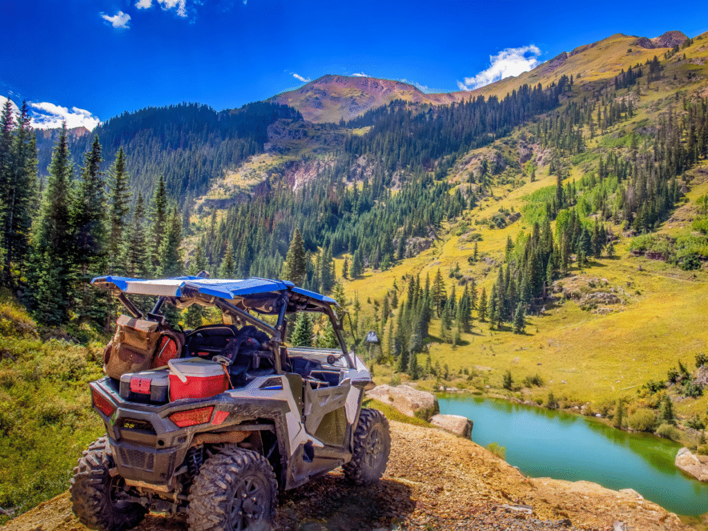 Um SXS alugado em uma trilha off-road acidentada com um lago pitoresco ao fundo