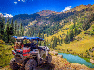 Um SXS alugado em uma trilha off-road acidentada com um lago pitoresco ao fundo